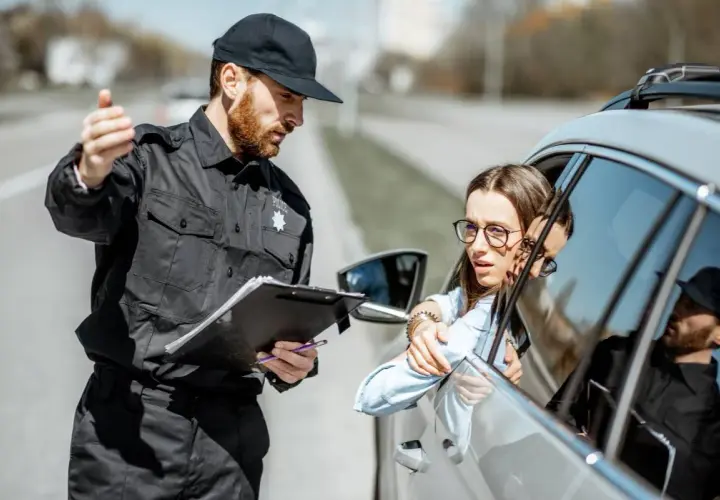 Policjant spisuje dane kierowcy. Zastanawia się, ile lat do policji potrzeba, by móc taką kontrolę przeprowadzać.