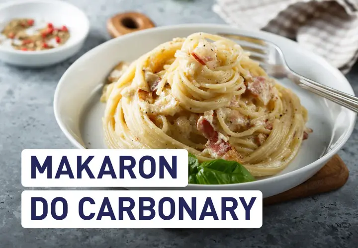 Pyszny makaron do carbonary z boczkiem i kremowym sosem, podany w białej misce. Obok przyprawy i liść bazylii.