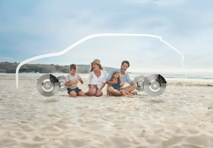Familie am Strand sitzt neben Bremsscheiben, mit einer weißen Autokontur darüber.