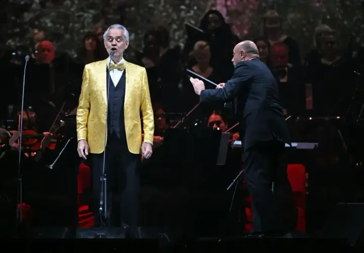 Andrea Bocelli w Polsce, w złotym fraku, śpiewa pod batutą dyrygenta.