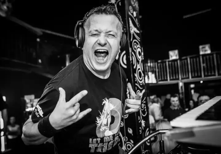 DJ Hazel w akcji, krzyczy z radością, ręce w geście rock and rolla. Sprawdź jego dj hazel cennik na imprezę!