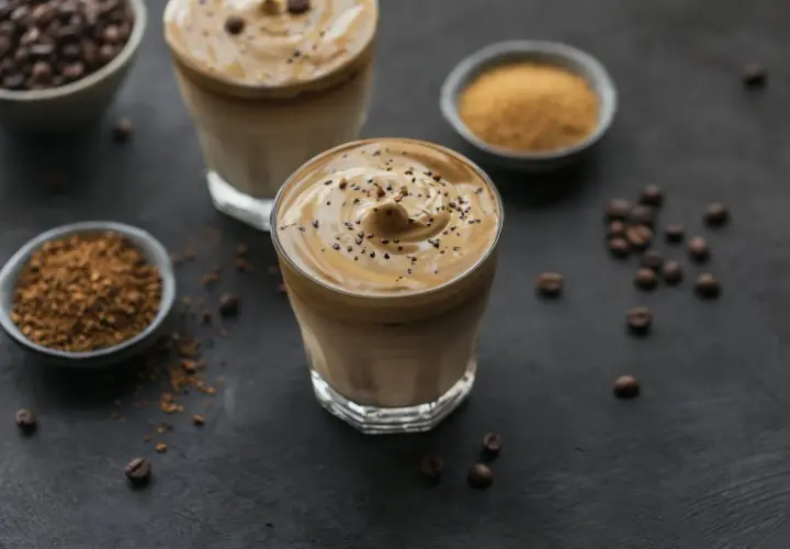 Dwa szklanki kawy mocha mousse z pianką i posypką z kawy. Obok miseczki z kawą rozpuszczalną i cukrem.