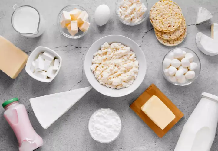 Różnorodne produkty bogate w wapń: mleko, sery, jogurt, masło, jajko i wafle ryżowe.
