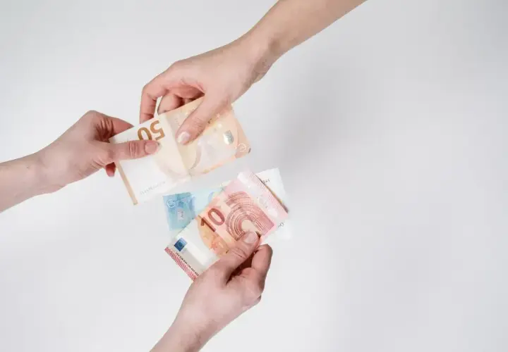 Dwie ręce przekazują sobie banknoty euro. W Holandii obowiązuje euro, więc to typowy widok.