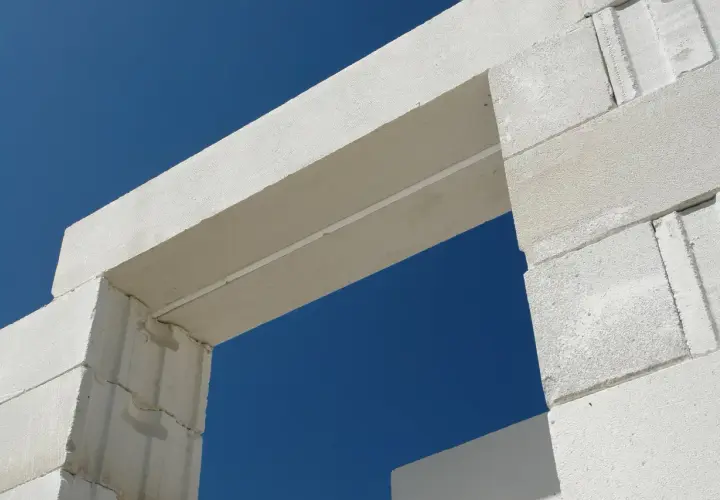 Białe nadproże nad drzwiami 80, wykonane z bloczków z betonu komórkowego, na tle błękitnego nieba.