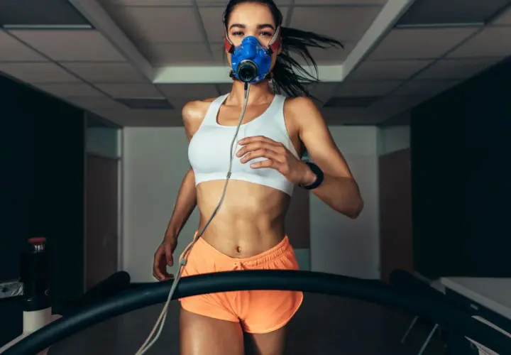 Kobieta w masce biegowa na bieżni, mierząca VO2max.