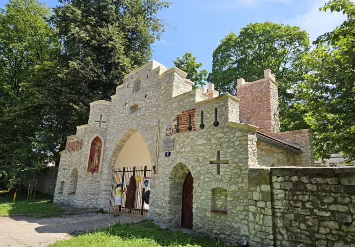 Kamienna brama z krzyżami i figurą świętego, przypominająca wejście do puszczy dulowskiej.