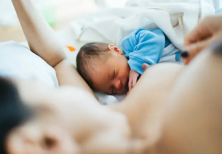 Malutki noworodek śpi wtulony w mamę. Jego brzuszek jest taki okrągły i słodki, jak u każdego niemowlaka.