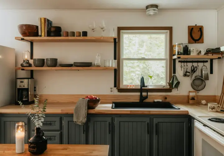 Cozy kitchen with dark gray cabinets, wooden countertops, and open shelving, perfect for an affordable kitchen makeover.