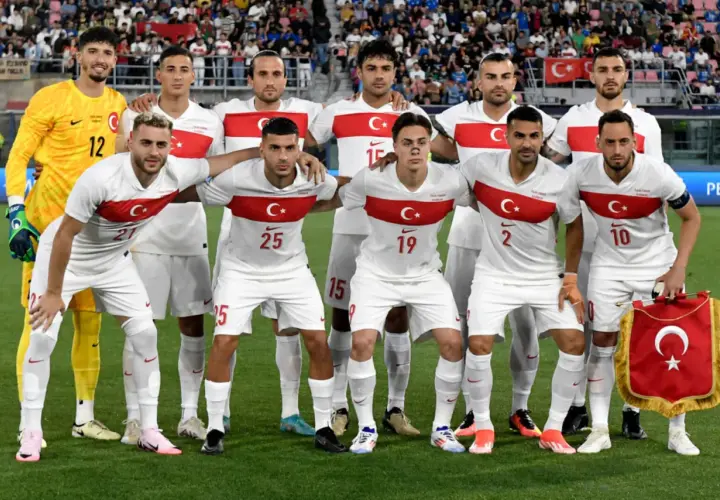 Piłkarze reprezentacji Polski i Turcji pozują do zdjęcia przed meczem. Białe stroje z czerwonym pasem i godłem.