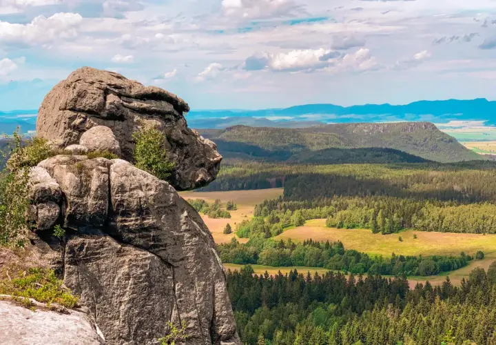 Majestatyczne, bledne skały górują nad zieloną doliną pełną lasów i pól. Widok zapiera dech w piersiach.