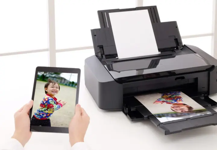 Drukarka atramentowa drukuje zdjęcie dziecka z tabletu. Wybór odpowiedni jaki papier fotograficzny do drukarki atramentowej zapewni najlepszą jakość.