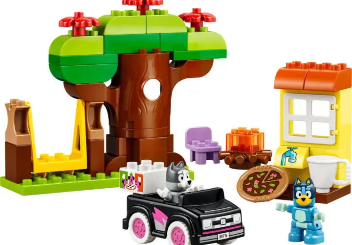 Bluey und Bingo spielen mit LEGO DUPLO im Wald. Ein Baumhaus, ein Auto und eine kleine Hütte sind aufgebaut.