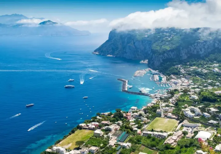 Widok na zatokę z łodziami i miasteczkiem na zboczu góry Capri.