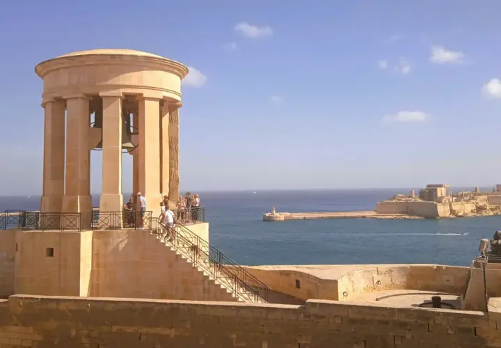Malta, kwiecień: słoneczna pogoda nad portem, widok na zabytkową wieżę z dzwonami i fortyfikacje.
