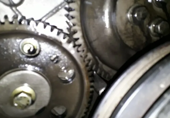 Zbliżenie na mechanizm zębatek, kluczowe dla ustawienia pompy wtryskowej Perkins 4. Widoczne śruby i smar.