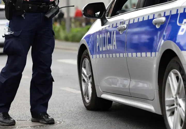 Policjant stoi obok radiowozu. Czy policja może zabrać telefon świadkowi? To pytanie nurtuje wielu.
