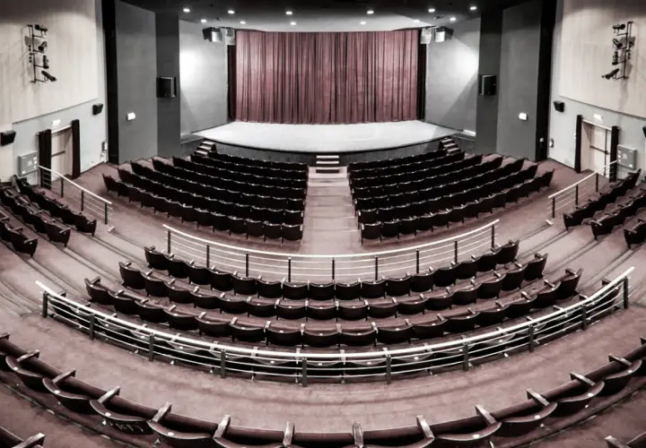 Pusta sala widowni w teatrze im. Aleksandra Sewruka w Elblągu, z rzędami czerwonych foteli i sceną w tle.