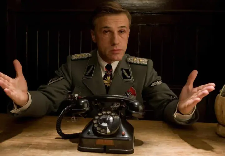 Colonnello Hans Landa, in uniforme, con le mani aperte, in una scena di "Bastardi senza gloria".