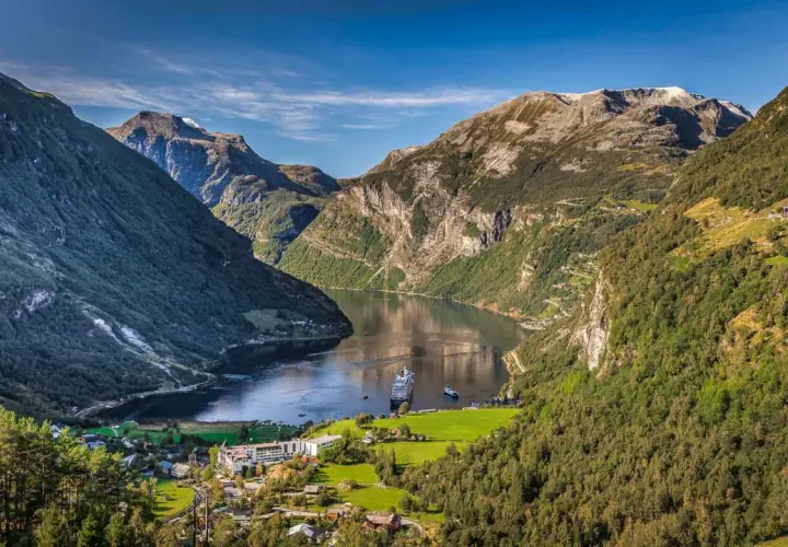Majestätische fjorde norwegen, mit einem Kreuzfahrtschiff auf dem ruhigen Wasser, umgeben von steilen, grünen Bergen und einem kleinen Dorf.