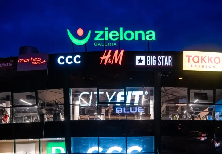 Nocny widok galerii handlowej z neonami sklepów: Zielona Galeria, CCC, H&M, Big Star, CityFit.