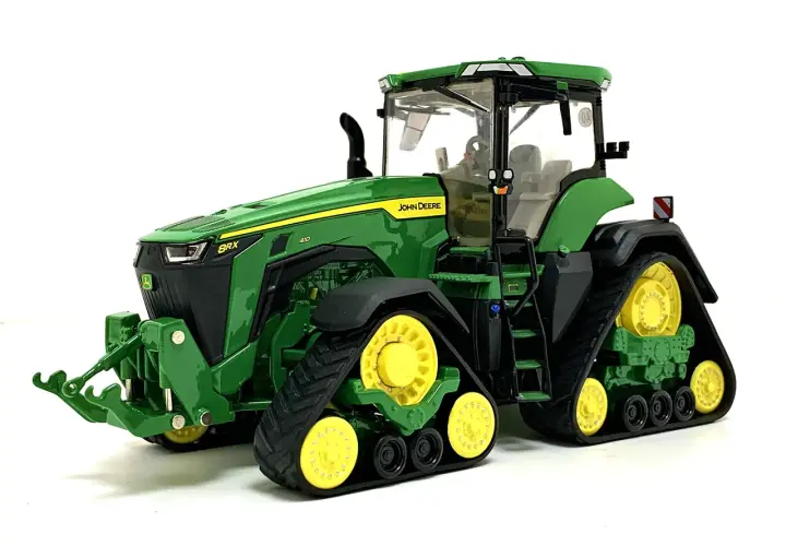 Zielony mini traktor John Deere z żółtymi kołami i gąsienicami, gotowy do pracy na farmie.
