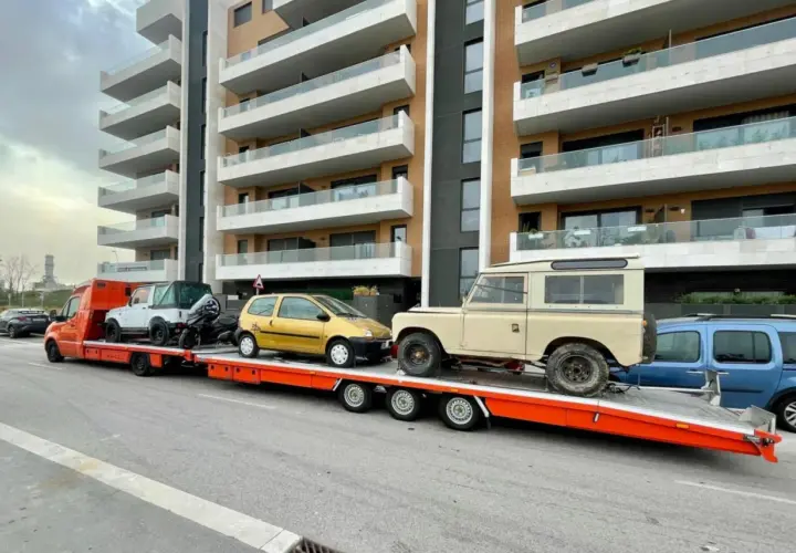 Laweta z autami: żółty Twingo, biały terenowy i beżowy Land Rover. B+E DMC.