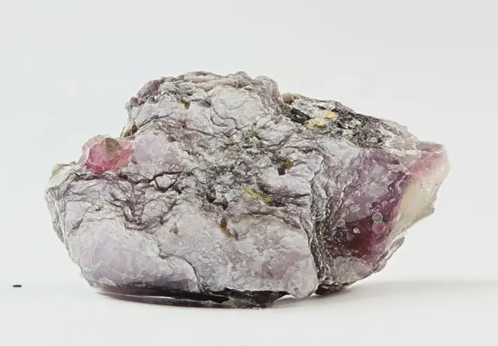 Ein schuppiger, lila-grauer Lepidolith-Stein mit glänzenden Oberflächen und einem kleinen, rosa Kristall.