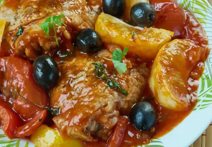 Un plat de daube de bœuf mijoté avec des tomates, des olives noires et des pommes de terre, garni de persil frais.