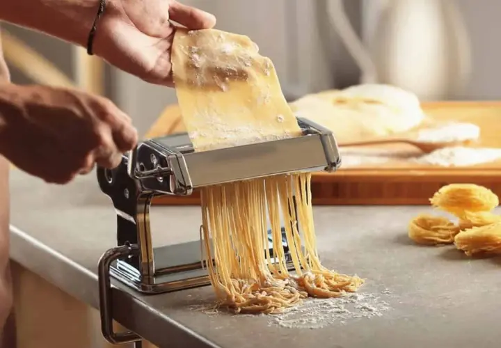 Préparation d'une recette de pâte italienne gastronomique. Une machine à pâtes produit des spaghettis frais, prêts à être cuisinés.