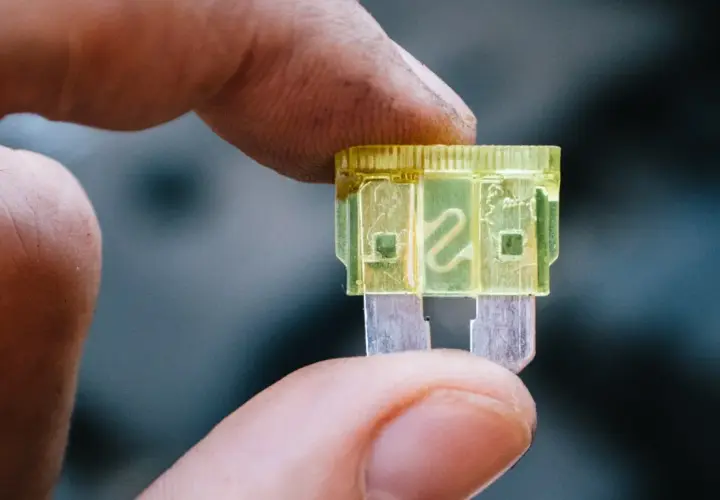 Dedo sostiene un fusible luz de freno amarillo de 20 amperios, listo para reemplazar uno quemado.