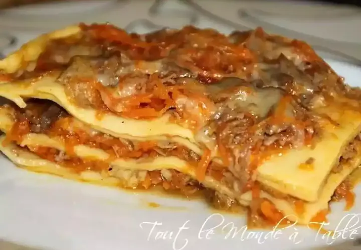 Une généreuse part de lasagne de canard, avec ses couches de pâtes, de viande effilochée et de sauce aux carottes, prête à être dégustée.
