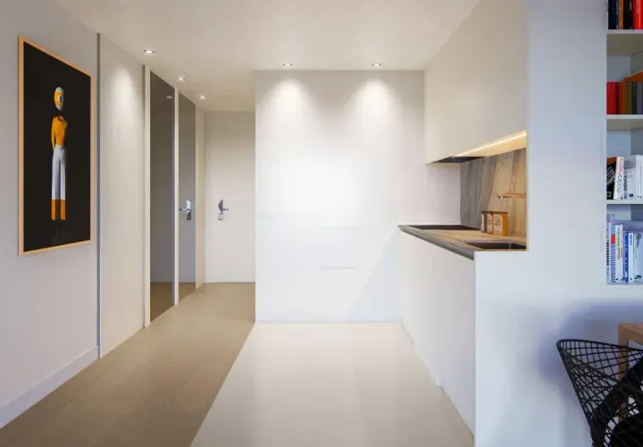 Pasillo moderno con arte abstracto y cocina minimalista, creando un ambiente de flujo luminoso.