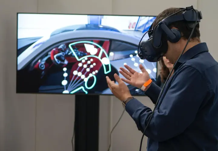 Un homme porte un casque de réalité augmentée, explorant un tableau de bord de voiture virtuel.