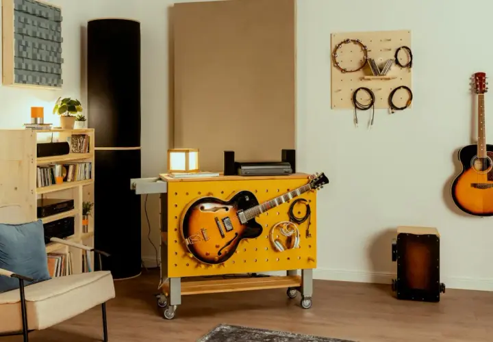 Kreative hobbykeller ideen: Gitarren, Kopfhörer und Kabel sind ordentlich an einer gelben Werkbank mit Lochwand befestigt. Akustikpaneele und weitere Instrumente schaffen eine musikalische Atmosphäre.