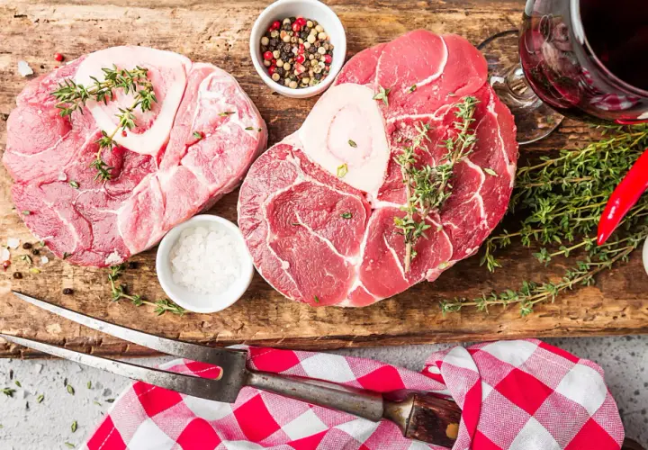 Deux belles pièces de viande blanche, du sel, des poivres, du thym et un piment rouge sur une planche en bois.