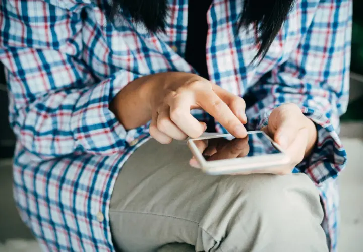 Mani che scorrono su uno smartphone, forse per esplorare il sexting perché si fa, un modo per connettersi.