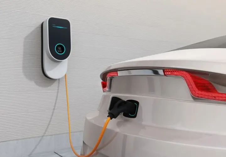 Nowoczesna stacja ładowania samochodów elektrycznych podłączona do białego auta. Sprawdź, jaka jest stacja ładowania samochodów elektrycznych cena.
