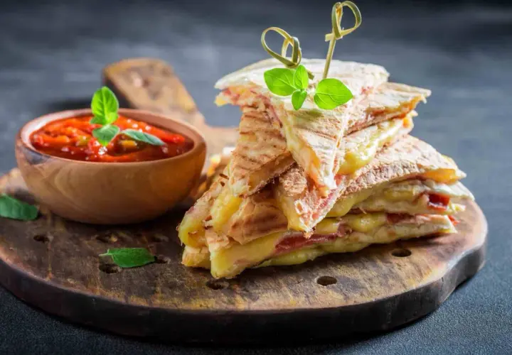 Pyszna tortilla z szynką i serem, podana z sosem pomidorowym. Idealna przekąska na szybki lunch.