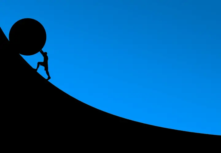 Silhouette d'un homme poussant une énorme sphère sur une pente. L'effort pour un prêt immobilier 30 ans.