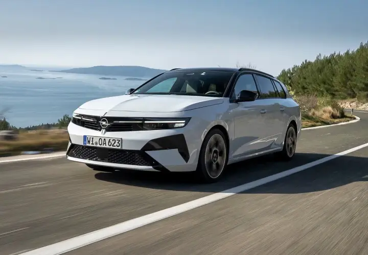 Biała Opel Astra Hybrid na krętej drodze nad morzem.