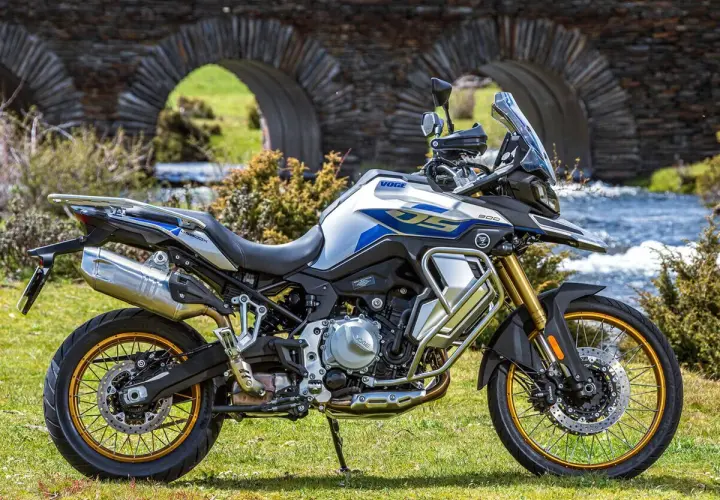 Moto Voge 500DS, una moto china con motor BMW, lista para la aventura junto a un puente de piedra.