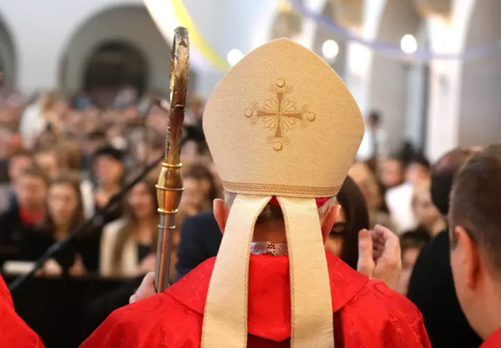 Biskup w mitrze i czerwonej szacie, trzymający pastorał, udziela sakramentu. Zastanawiasz się, ile trwa bierzmowanie?