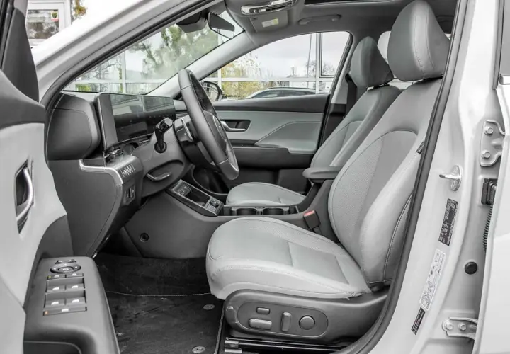 Wnętrze Hyundai Kona Hybrid z jasnoszarymi skórzanymi fotelami, nowoczesnym panelem sterowania i dużym ekranem multimedialnym.