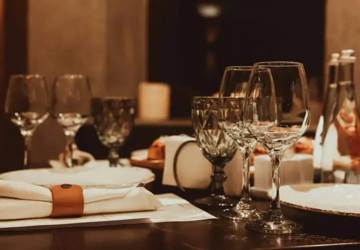 Table dressée avec verres à vin, serviette et bouteille d'eau.