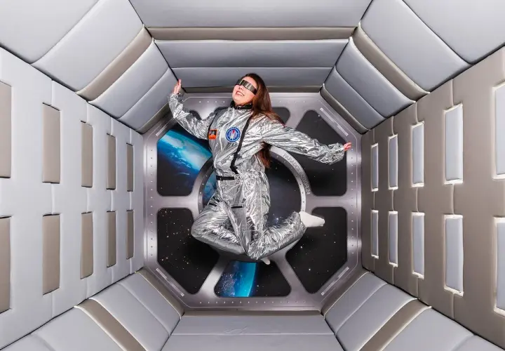 En person i rymddräkt svävar i en futuristisk tunnel, en del av en museum illusion i Stockholm.