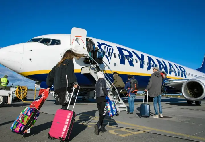 Odprawa Ryanair: pasażerowie z walizkami wchodzą po schodkach do samolotu.