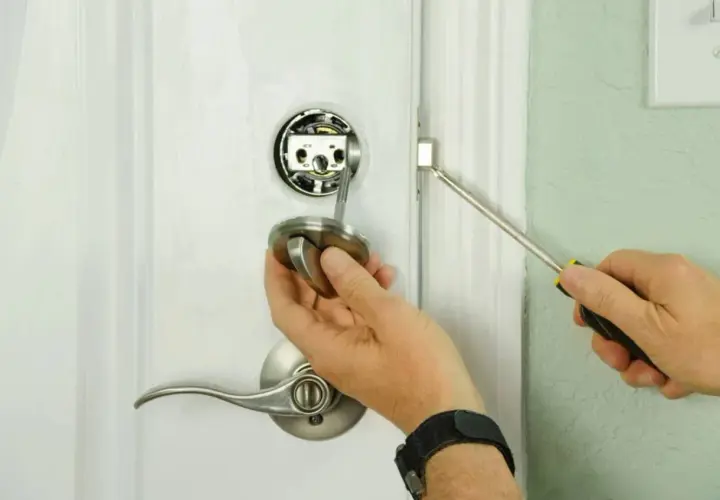 Main tenant démonte une poignée de porte pour savoir comment ouvrir une porte de chambre bloquée.
