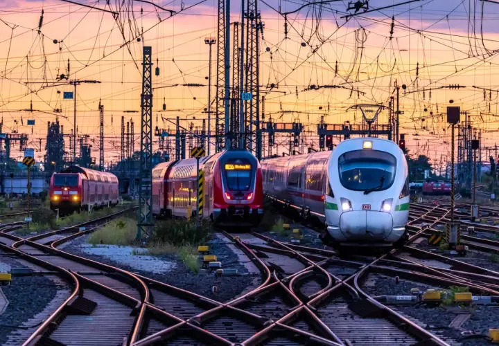 Mehrere Züge auf Bahngleisen bei Sonnenuntergang. Das Deutschlandticket gilt einen Monat lang.