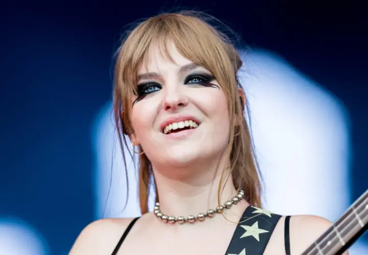 Victoria De Angelis z Måneskin, z charakterystycznym makijażem oczu, uśmiecha się podczas występu.